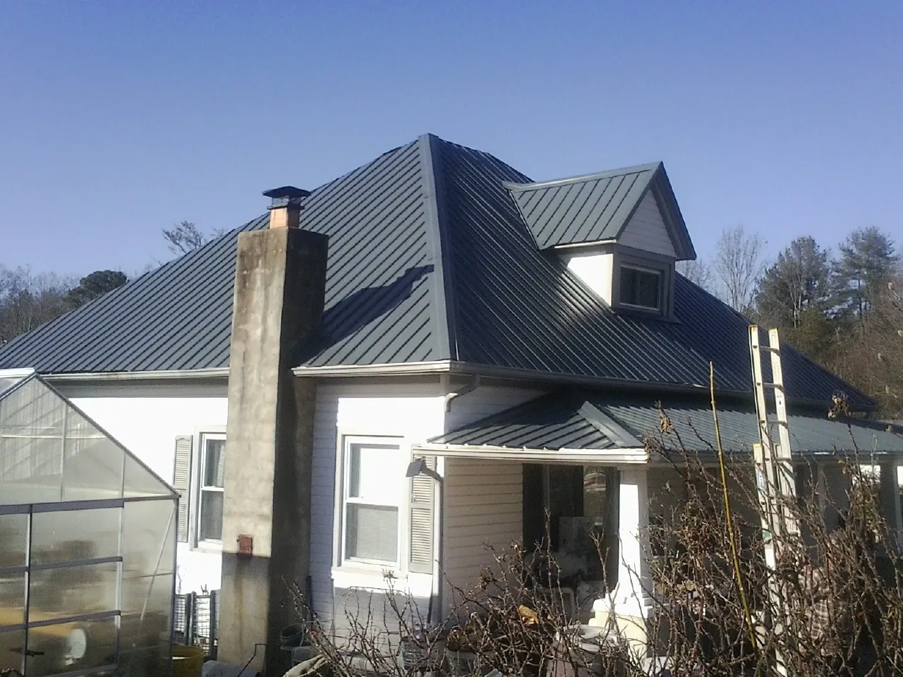 Dark blue standing seam metal roof on a white farmhouse with dormer — Slate & Tile Roof Repair by Roofing Brothers in New Middletown