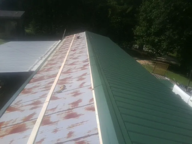 Old rusted panels beside newly installed green metal roofing — Wind Damage Roof Repair by Roofing Brothers in New Middletown
