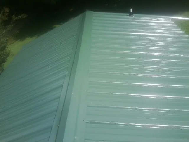 New green metal panels meeting at the ridge of a roof — Flat Roof Repair work by our crew in New Middletown