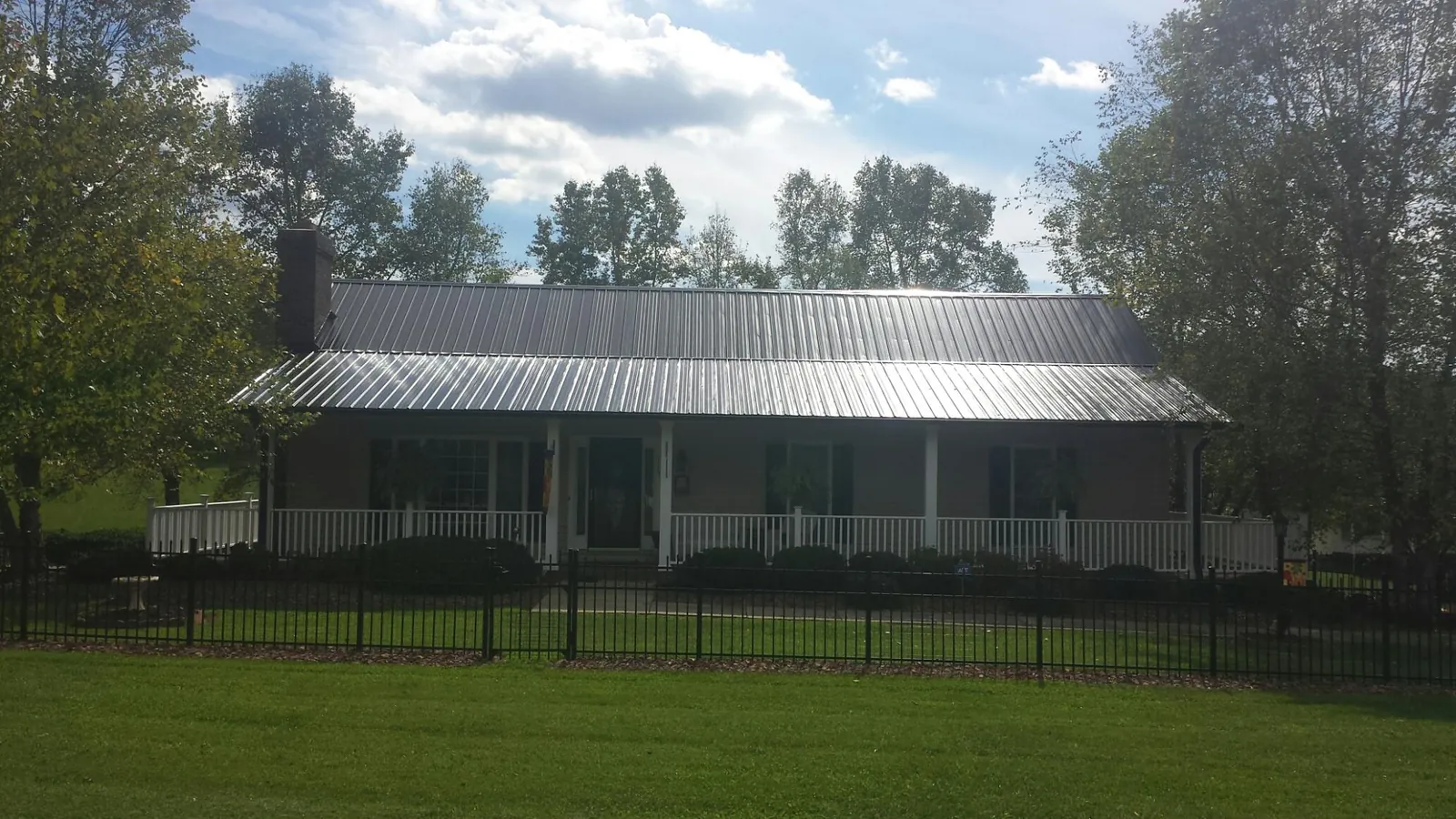 Gray metal roof on a brick ranch with a full width front porch — Gutter Guard Installation work by our crew in New Middletown