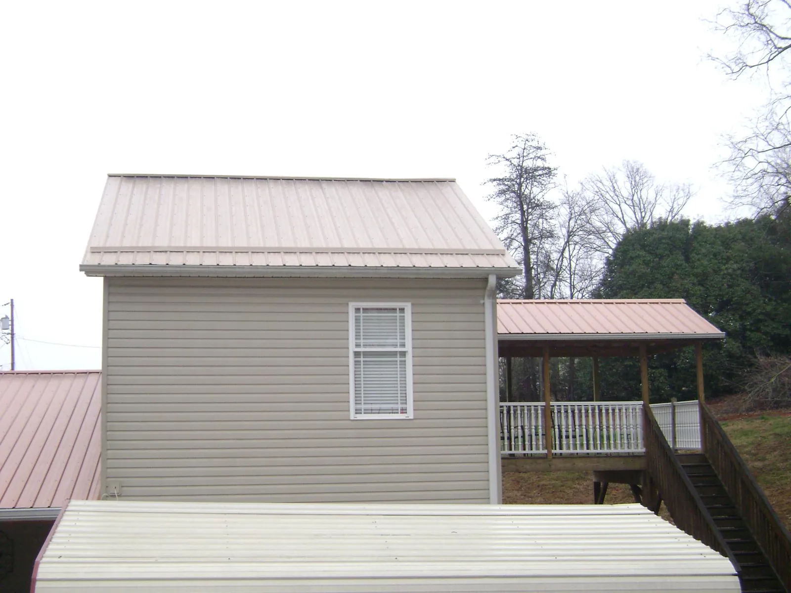 Tan metal roofs on a two story addition and attached porch, from a Roof Replacement job in New Middletown