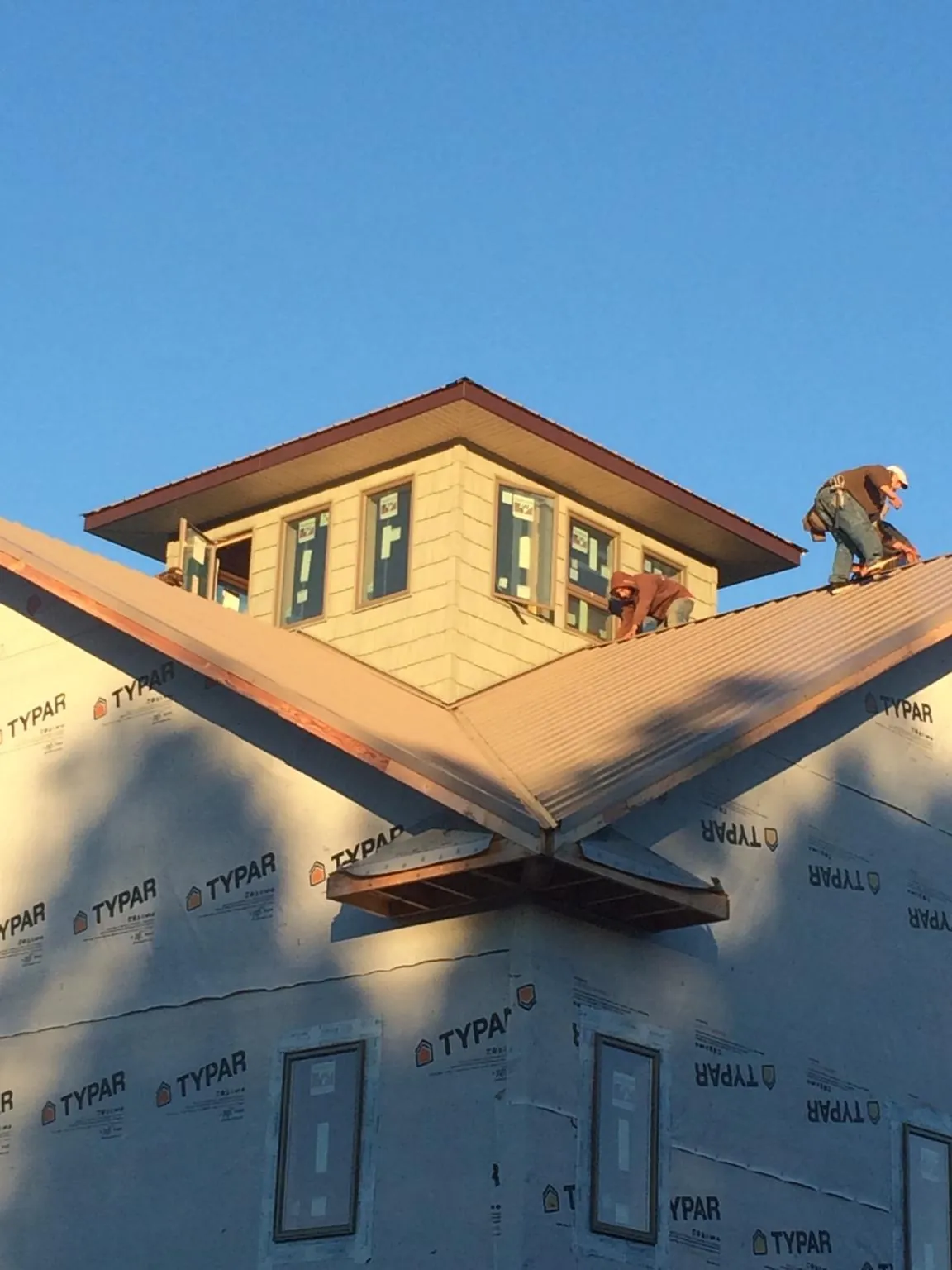 Roofers working around a rooftop cupola on a new metal roof at sunset — Roof Waterproofing in New Middletown by Roofing Brothers